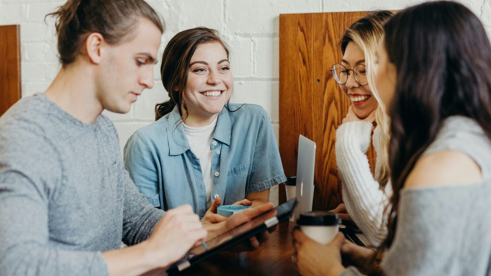 A team with their laptops and tablets discusses strategy around a table